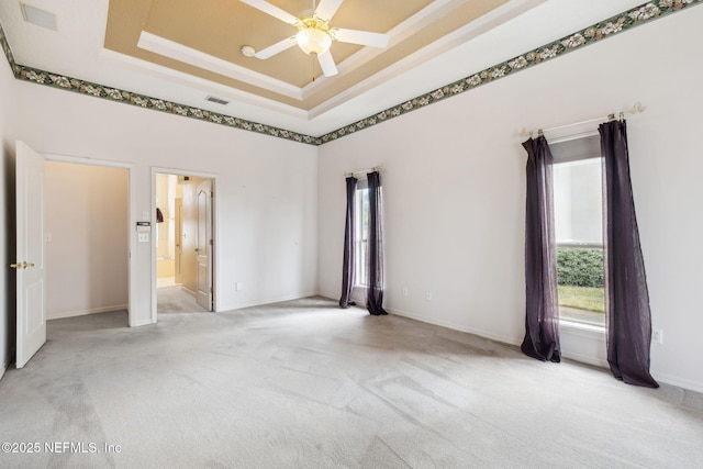 unfurnished room with visible vents, ceiling fan, a tray ceiling, crown molding, and carpet flooring