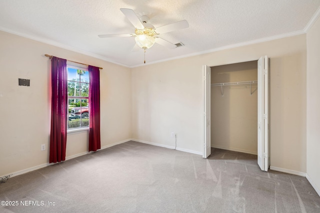 unfurnished bedroom with ornamental molding, carpet, a textured ceiling, and baseboards