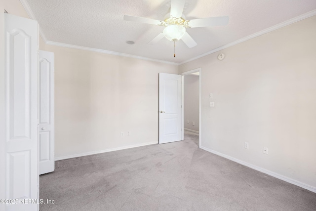 spare room featuring ornamental molding, carpet flooring, ceiling fan, a textured ceiling, and baseboards