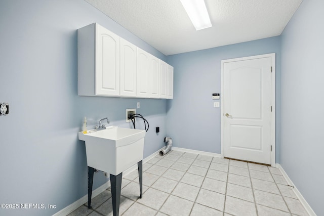 laundry area with a textured ceiling, light tile patterned floors, washer hookup, baseboards, and cabinet space