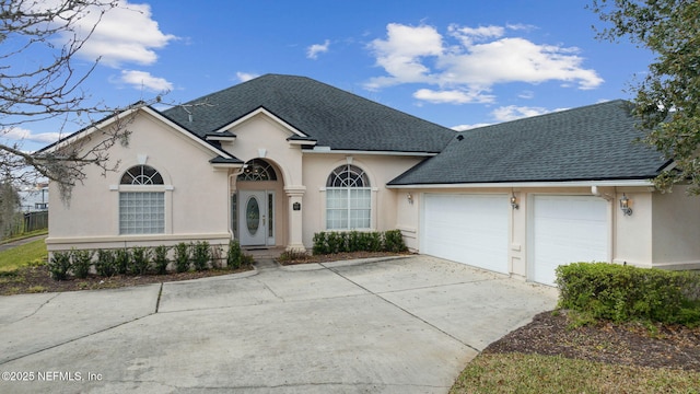 view of front of property with driveway, a shingled roof, an attached garage, and stucco siding