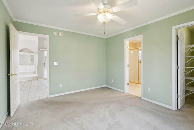 unfurnished bedroom featuring carpet floors, ornamental molding, ensuite bath, and baseboards