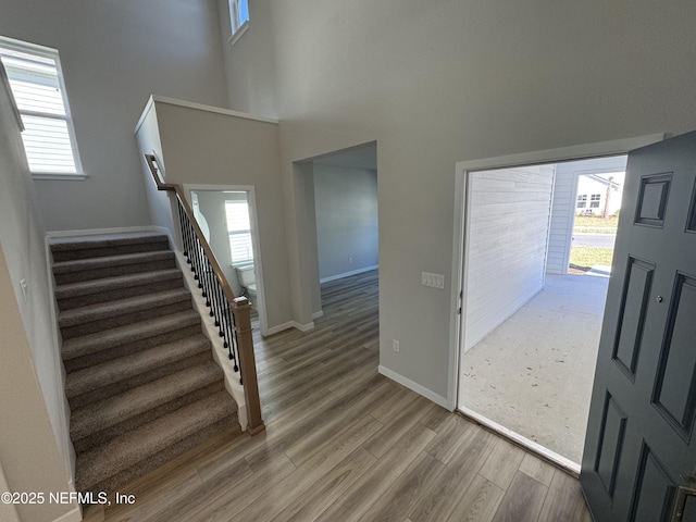 foyer entrance featuring stairs, a high ceiling, baseboards, and wood finished floors