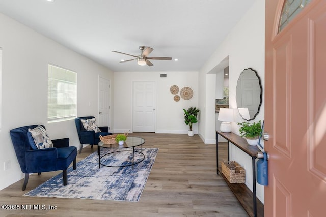 living area featuring baseboards, visible vents, a ceiling fan, and wood finished floors