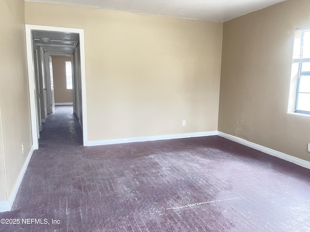 spare room featuring baseboards and wood finished floors