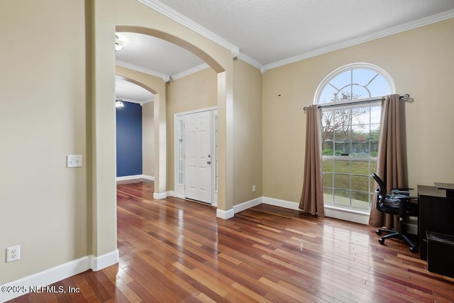 office space featuring ornamental molding, arched walkways, baseboards, and hardwood / wood-style flooring