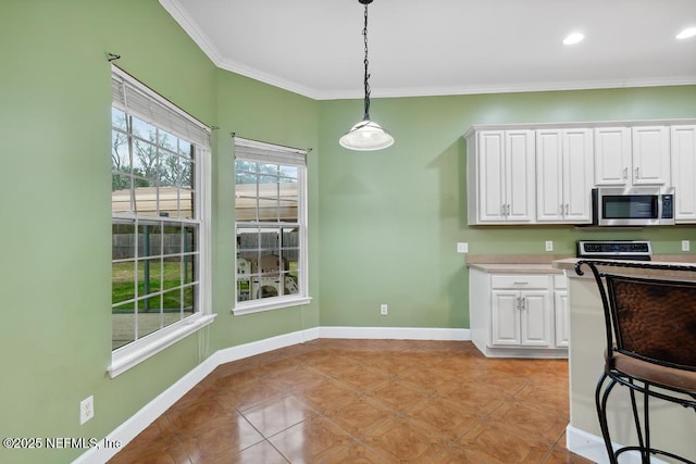 kitchen featuring ornamental molding, stainless steel microwave, baseboards, and white cabinetry