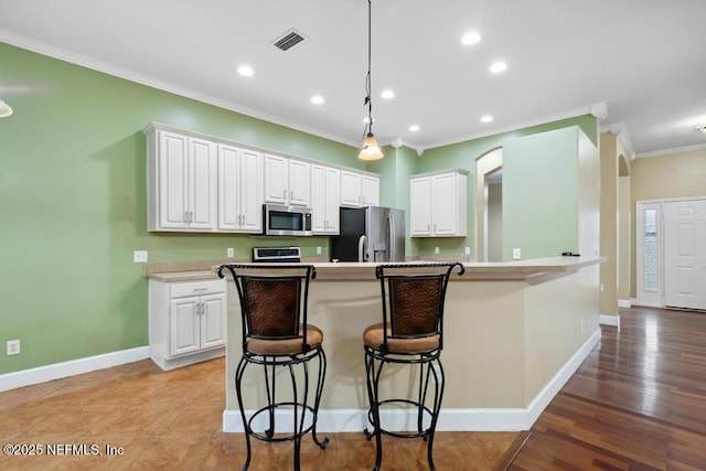 kitchen with white cabinetry, visible vents, a kitchen breakfast bar, appliances with stainless steel finishes, and crown molding