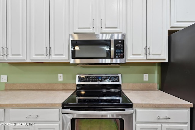 kitchen featuring stainless steel appliances, light countertops, and white cabinetry