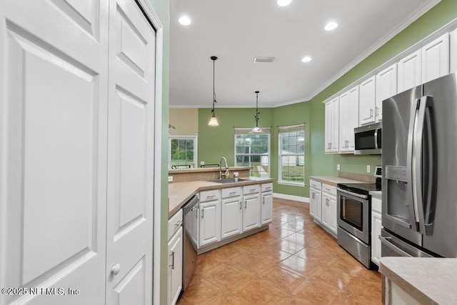 kitchen with white cabinets, ornamental molding, stainless steel appliances, and a sink