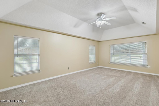 carpeted empty room featuring a wealth of natural light, visible vents, vaulted ceiling, and a textured ceiling