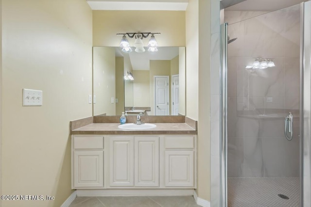 bathroom with baseboards, a shower stall, vanity, and tile patterned floors