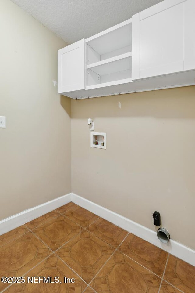 washroom featuring washer hookup, cabinet space, a textured ceiling, tile patterned flooring, and baseboards