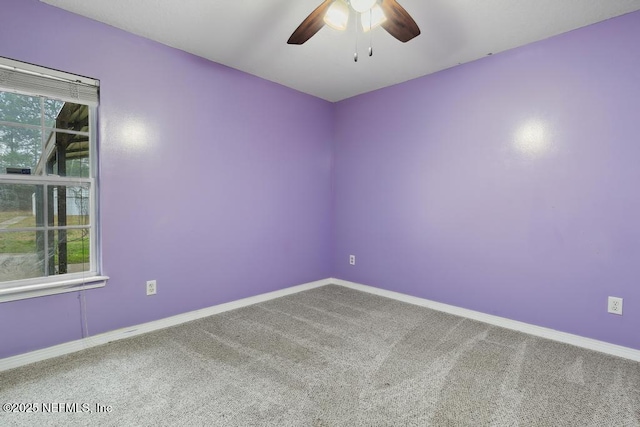 carpeted empty room featuring ceiling fan and baseboards