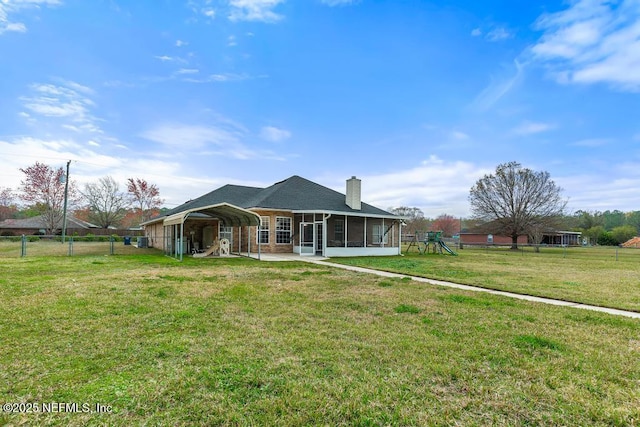 view of front of home with a playground, a sunroom, a carport, a chimney, and a front yard