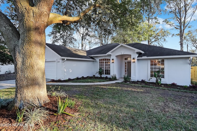 ranch-style home featuring a garage, a front yard, and stucco siding