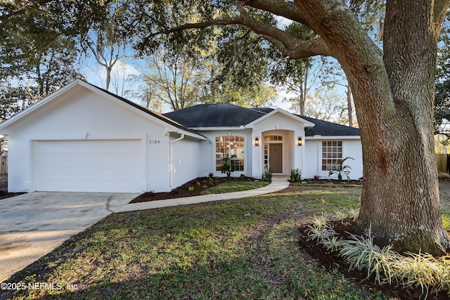 single story home with a front lawn, concrete driveway, an attached garage, and stucco siding