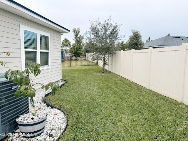 view of yard featuring a fenced backyard and central AC