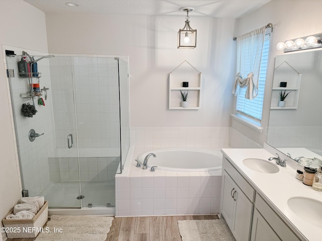 full bathroom with a garden tub, a shower stall, a sink, and wood finished floors