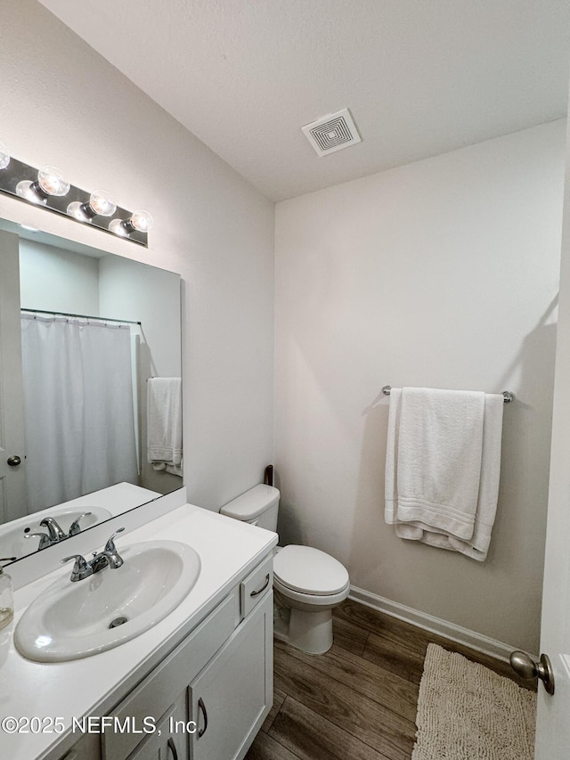 full bathroom with toilet, wood finished floors, vanity, visible vents, and baseboards