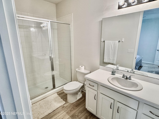 ensuite bathroom with toilet, wood finished floors, vanity, a stall shower, and ensuite bath