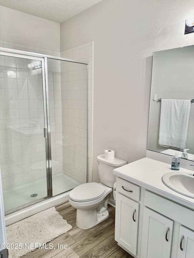 full bath with vanity, wood finished floors, toilet, and a shower stall