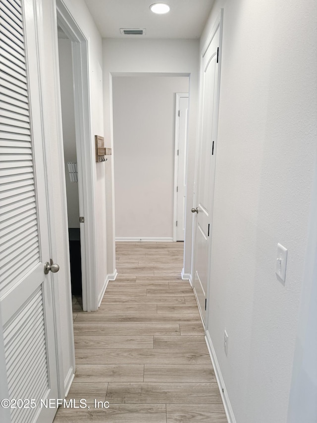 hall featuring light wood-type flooring, baseboards, visible vents, and recessed lighting