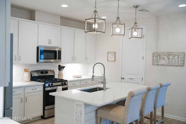 kitchen featuring hanging light fixtures, appliances with stainless steel finishes, light countertops, and white cabinets