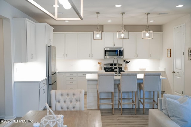 kitchen with white cabinetry, stainless steel appliances, light countertops, and decorative light fixtures