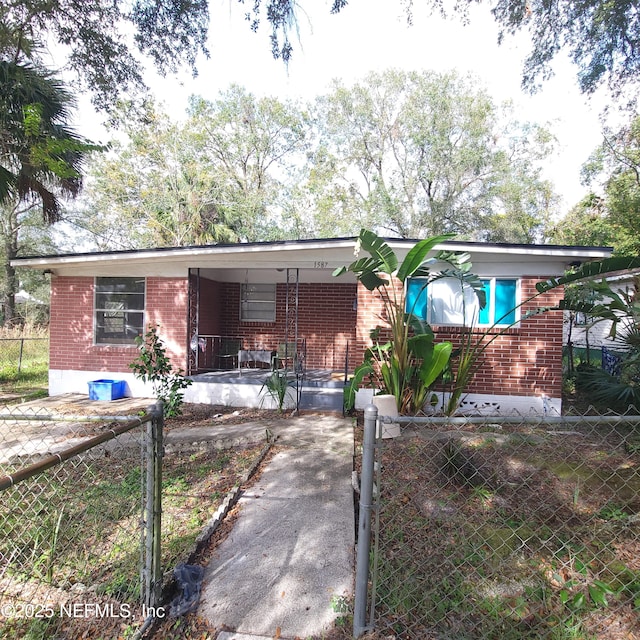 view of front of property featuring brick siding, a fenced front yard, and a porch