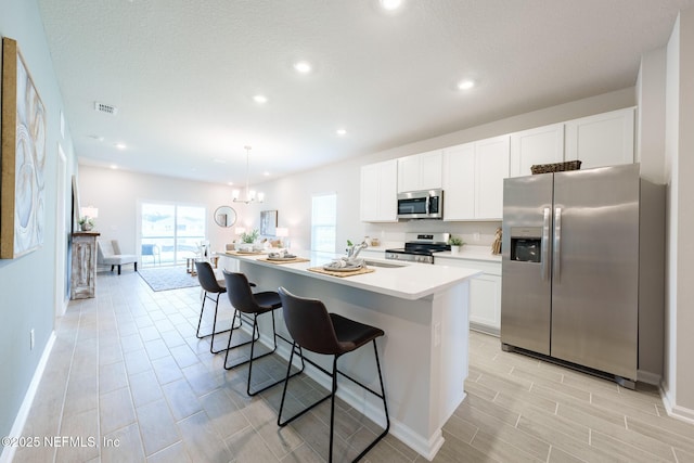 kitchen featuring stainless steel appliances, light countertops, white cabinets, a kitchen island, and a kitchen bar