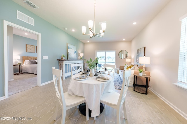 dining room featuring a chandelier, wood tiled floor, visible vents, and baseboards