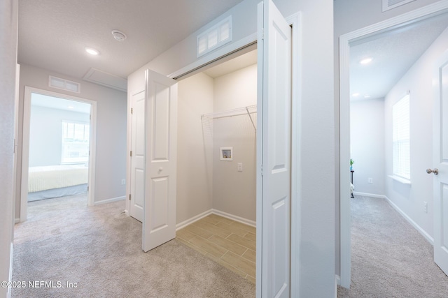 corridor with a healthy amount of sunlight, baseboards, and light colored carpet