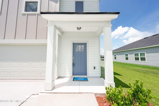 view of exterior entry with a garage, a porch, board and batten siding, and a yard