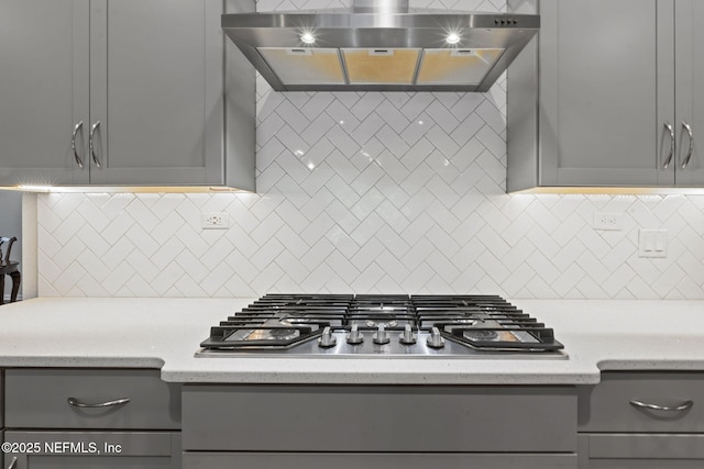 352 Bronson Pkwy, Saint Augustine, FL 32095 - kitchen with gray cabinetry, range hood, stainless steel gas cooktop, and backsplash