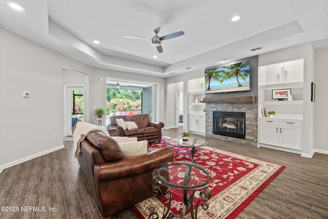 352 Bronson Pkwy, Saint Augustine, FL 32095 - living area featuring a raised ceiling, a textured ceiling, a fireplace, a ceiling fan, and wood finished floors