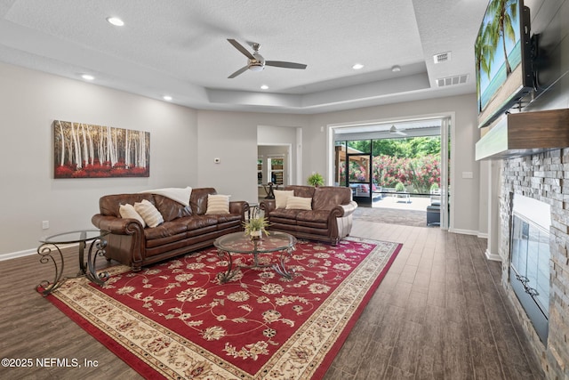 352 Bronson Pkwy, Saint Augustine, FL 32095 - living room with a textured ceiling, a glass covered fireplace, ceiling fan, dark wood-style flooring, and a raised ceiling
