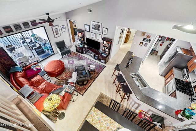 living room with high vaulted ceiling, visible vents, and a ceiling fan