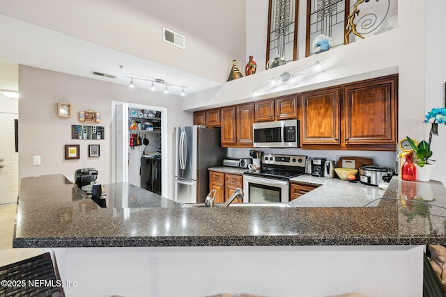 kitchen featuring a peninsula, a towering ceiling, visible vents, and stainless steel appliances