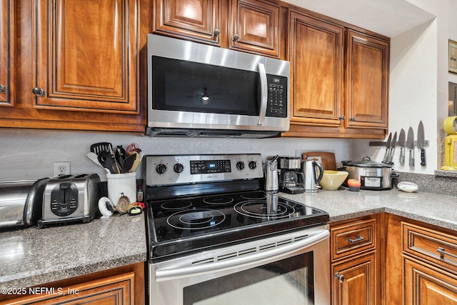 kitchen featuring stainless steel appliances, brown cabinetry, and light countertops