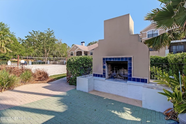 view of patio / terrace featuring fence, a tiled fireplace, and volleyball court