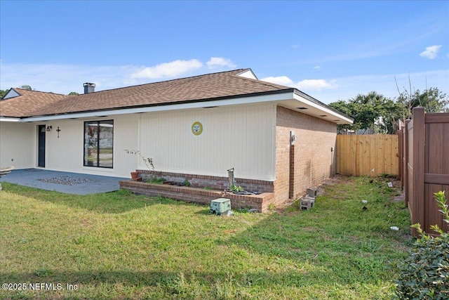 rear view of property with brick siding, fence, a lawn, and a patio