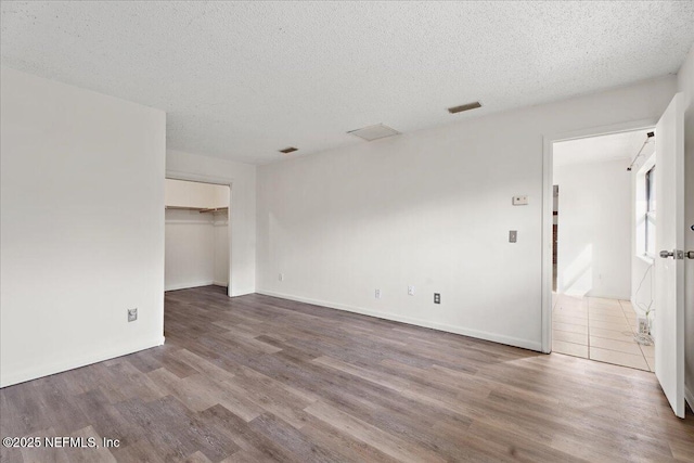 spare room with visible vents, a textured ceiling, and wood finished floors