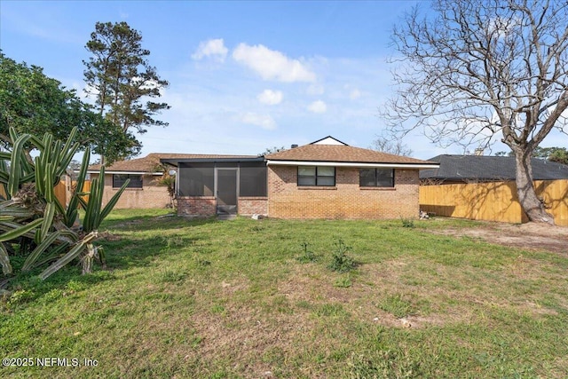 rear view of property with a sunroom, a lawn, and fence