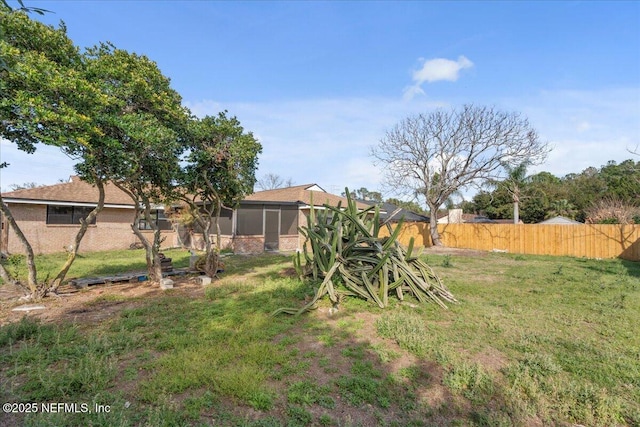 view of yard featuring a sunroom and a fenced backyard