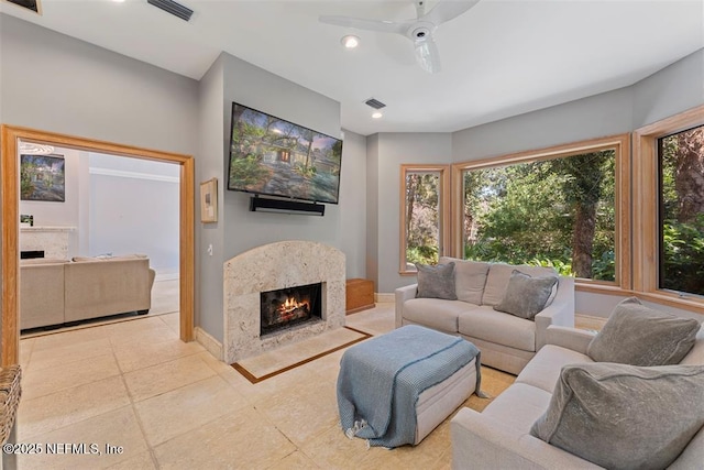 tiled living room with visible vents, baseboards, ceiling fan, and a high end fireplace