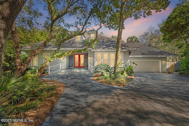 cape cod home with french doors, a garage, and driveway