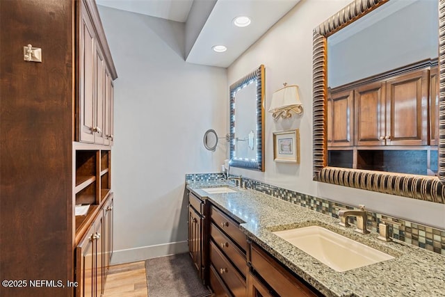 bathroom featuring a sink, baseboards, wood finished floors, and double vanity