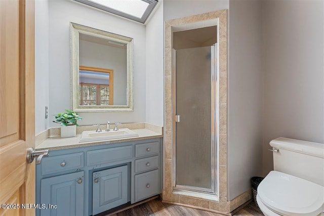 bathroom with vanity, toilet, wood finished floors, and a stall shower