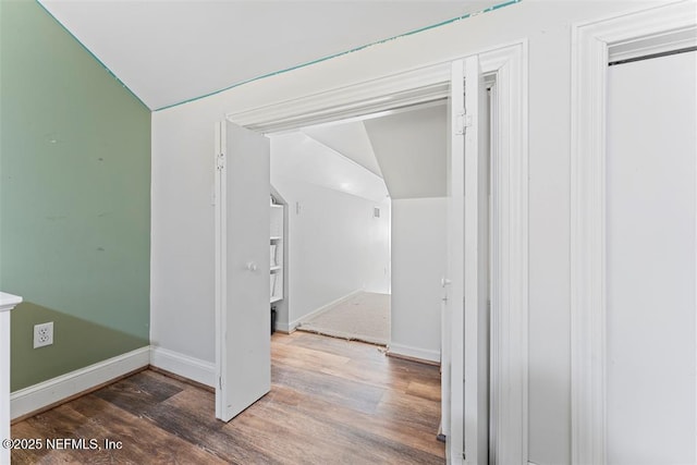 hall featuring vaulted ceiling, wood finished floors, and baseboards